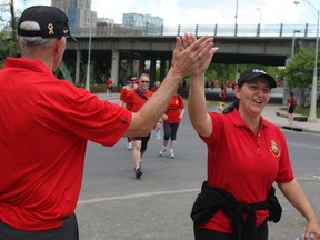 Vice-Chief of the Defence Staff, Lt.-Gen. Guy Thibault gives high-fives​ those who finished the 8km run or 4 km walk as they arrived at Confederation Park. 
(DOUG HEMPSTEAD/Ottawa Sun)
