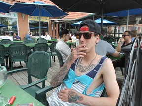 Alex Tremblay puffs on a cigarette at Saffron's Restaurant on Corydon Avenue in Winnipeg, Man., on Fri., May 30, 2014. A survey suggests about two-thirds of Manitobans support extending smoking bans to outdoor patios of restaurants and bars. Kevin King/Winnipeg Sun/QMI Agency