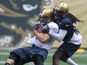 Slotback Taylor Renaud hangs onto the ball while being tackled by defensive back Brandon Hogan during Winnipeg Blue Bombers rookie camp at Investors Group Field in Winnipeg, Man., on Fri., May 30, 2014. Kevin King/Winnipeg Sun/QMI Agency