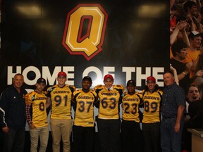 Gaels head coach Pat Sheahan, left, and defensive co-ordinator Greg Marshall, right, stand with the group of newest recruits to the Queen's University football program at a news conference on Friday. (Queen's University Athletics)