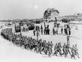 German prisoners-of-war march along Juno Beach landing area to a ship taking them to England after they were captured by Canadian troops at Bernieres Sur Mer, France on June 6, 1944 as allied soldiers descended on the beaches of Normandy for D-Day — an operation that turned the tide of the Second World War against the Nazis, marking the beginning of the end of the conflict. (National Archives of Canada photo)
