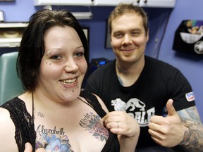 Rebecca Ellis (l) and Aarom Hemmersbach display her tattoo replacements at Iron Lotus Body Art in Winnipeg, Man. Wednesday May 28, 2014.(Brian Donogh/Winnipeg Sun/QMI Agency)