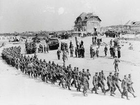 German prisoners-of-war march along Juno Beach landing area to a ship taking them to England after they were captured by Canadian troops at Bernieres Sur Mer, France on June 6, 1944 as allied soldiers descended on the beaches of Normandy for D-Day — an operation that turned the tide of the Second World War against the Nazis, marking the beginning of the end of the conflict. (National Archives of Canada photo)