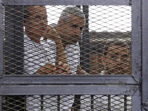 Al Jazeera journalists (L-R) Peter Greste, Mohammed Fahmy and Baher Mohamed stand behind bars at a court in Cairo June 1, 2014. The trial of the three Al Jazeera journalists accused of aiding of a terrorist organisation has been postponed to June 6. REUTERS/Asmaa Waguih
