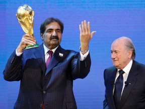 Qatar's Emir Sheikh Hamad bin Khalifa al Thani (left) holds up a copy of the World Cup he received from FIFA president Sepp Blatter after the announcement that Qatar will host the FIFA World Cup 2022 in this December 2, 2010 file photograph.  (REUTERS/Christian Hartmann/Files)