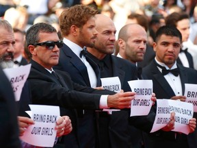 Actors Mel Gibson and Antonio Banderas, cast members of the film "The Expendables 3", hold placards which read "Bring back our girls" as they pose on the red carpet during the 67th Cannes Film Festival in Cannes May 18, 2014. From L, Mel Gibson, Antonio Banderas, Kellan Lutz, Randy Couture, Jason Statham, Victor Ortiz.          REUTERS/Yves Herman