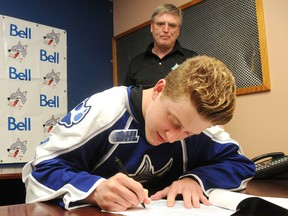 Sudbury Wolves general manager Blaine Smith looks on as 2014 first-round pick Michael Pezzatta signs with the local OHL team Saturday. Smith said the Wolves won't sign any of their other 2014 draft picks until training camp.