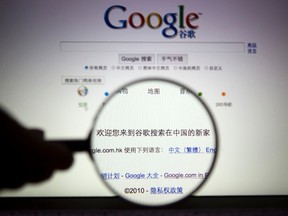 A person poses with a magnifying glass in front of a Google search page in this illustrative photograph taken in Shanghai in this March 23, 2010 file photo. REUTERS/STRINGER