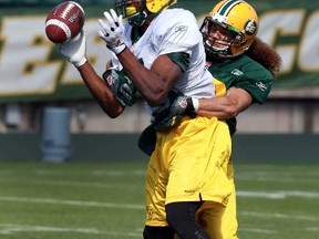 Shamawd Chambers jumps for a pass under the coverage of Aaron Grymes during training camp at Commonwealth Stadium in Edmonton, Alta., on Wednesday, June 4, 2014.  Perry Mah/ Edmonton Sun/ QMI Agency