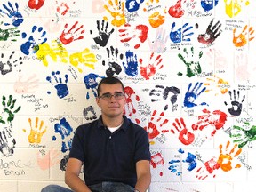 Student Sam Wenske shows a mural with student handprints at Sir George Ross secondary school, which closes this year in a merger. (Derek Ruttan/ The London Free Press)