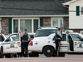 Codiac RCMP officers take cover behind their vehicle in Moncton, New Brunswick June 4, 2014. Three police officers were shot dead and two more were wounded, police said as they conducted a manhunt for a man carrying a rifle and wearing camouflage clothes. Police said they were searching for Justin Bourque, 24, of Moncton.   (REUTERS/Viktor Pivarov/Moncton Times & Transcript)
