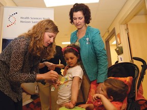 JOHN LAPPA/THE SUDBURY STAR
Dr. Amy Blair, left, demonstrates an allergy test with Gabriella Serafini, 6, during a press conference at Health Sciences North new pediatric allergy clinic on Wednesday. Looking on is Gabriella's mother, Jenna, and her brother, Emilio, 2.