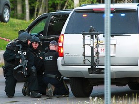 Emergency Response team members take cover behind vehicles in Moncton, N.B., on June 4, 2014. (REUTERS/Ron Ward/Moncton Times & Transcript)