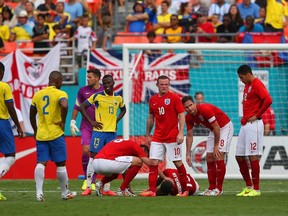 Frank Lampard and Rickie Lambert of England check on injured Alex Oxlade-Chamberlain of England as he lies on the pitch during the International friendly match between England and Ecuador at Sun Life Stadium on June 4, 2014 in Miami Gardens, Florida. (Richard Heathcote/Getty Images/AFP)