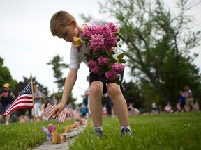 Alex Teeter, 8, places flowers on the grave sites of Battle of Gettysburg soldiers during a ceremony at National Soldier's Cemetery following the Gettysburg Memorial Day parade in Gettysburg, Pennsylvania, May 26, 2014. REUTERS/Mark Makela