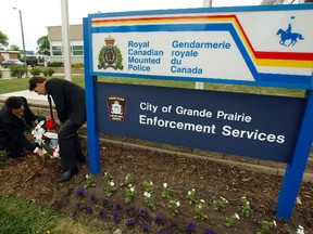 Shane Smith (left) and Eugene Krause glance toward the Alberta, Canada and Grande Prairie flags flying at half mast at the Grande Prairie RCMP detachment on 99 Street on Thursday, June 5, 2014. Smith and Krause were recognizing three members of the RCMP that were shot and killed and another two members suffered injuries from a gunshot on Wednesday in Moncton, New Brunswick. TOM BATEMAN/DAILY HERALD-TRIBUNE/QMI AGENCY