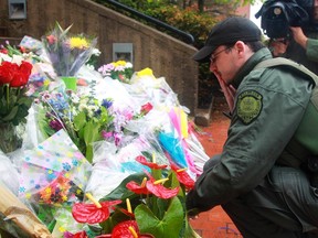 A man pauses after leaving flowers on the steps of RCMP headquarters  in Moncton, New Brunswick June 6, 2014.  Canadian police have arrested a man suspected of having shot dead three police officers and wounding two more, ending a massive manhunt, the police said on Friday. The shooting in the eastern city of Moncton was one of the worst of its kind in Canada, where gun laws are stricter than in the United States and deadly attacks on police are rare.  REUTERS/Christinne Muschi(CANADA - Tags: CRIME LAW)