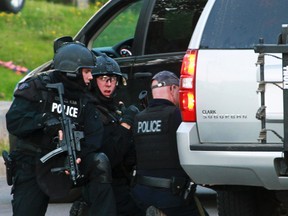 QMI WIRE PHOTOS OF THE WEEK JUNE 6TH - Emergency Response team members take cover behind vehicles in Moncton, New Brunswick June 4, 2014. Three police officers were shot dead and two more were wounded, police said as they conducted a manhunt for a man carrying a rifle and wearing camouflage clothes. Police said they were searching for Justin Bourque, 24, of Moncton. REUTERS/Ron Ward/Moncton Times & Transcript
