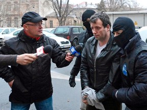 Marcel Lazar Lehel, 40, is escorted by masked policemen in Bucharest, after being arrested in Arad, 550 km (337 miles) west of Bucharest Jan. 22, 2014. REUTERS/Mediafax/Silviu Matei
