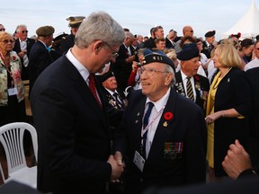 Prime Minister Stephen Harper, left, speaks with Canadian veteran Barry Wilson after a Canadian-French D-Day ceremony at the Juno Beach Centre in Courseulles sur Mer, June 6, 2014. World leaders and veterans gathered by the beaches of Normandy on Friday to mark the 70th anniversary of World War Two's D-Day landings. (REUTERS/Chris Helgren)