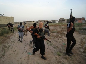 Masked Sunni gunmen walk with their weapons during a patrol outside the city of Falluja, Iraq in this April 28, 2014 file photo. REUTERS/Stringer