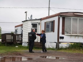 An RCMP officer is shown support and offered condolences by a postal worker passing by a home, which according to local media was where Justin Bourque resided, in a trailer park in Moncton, New Brunswick June 7, 2014.  REUTERS/Christinne Muschi