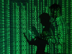 An illustration picture shows a projection of binary code on a man holding a laptop computer, in an office in Warsaw June 24, 2013. REUTERS/Kacper Pempel