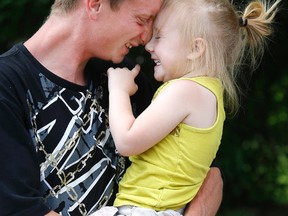 Dylon Keast hugs his two-year-old daughter Mackenzie a day after a fatal fire in Brampton. (CRAIG ROBERTSON, Toronto Sun)