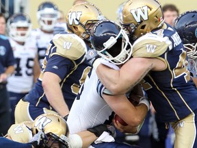 Toronto Argonauts quarterback Mitchell Gale (c) loses his helmet while being sacked by Winnipeg Blue Bombers defensive end Zach Anderson during CFL football in Winnipeg, Man. Monday June 09, 2014.
Brian Donogh/Winnipeg Sun/QMI Agency