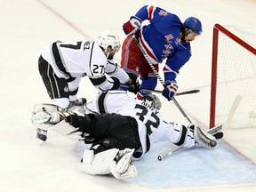 Kings goaltender Jonathan Quick dives to make a save as defenceman Alec Martinez tries to hold off Rangers winger Mats Zuccarello during the first period on Monday night. (USA TODAY/PHOTO)