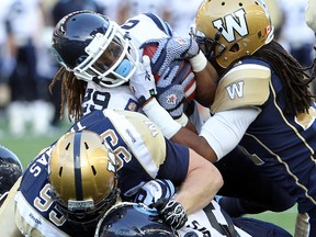 Argonauts running back Curtis Steele (centre) is brought down by Blue Bombers defensive tackle Jake Thomas in CFL pre-season action on Monday night. (QMI AGENCY)
