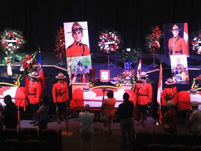 Members of the public file past the caskets of the fallen RCMP constables Monday at Wesleyan Celebration Centre in Moncton. (REUTERS)