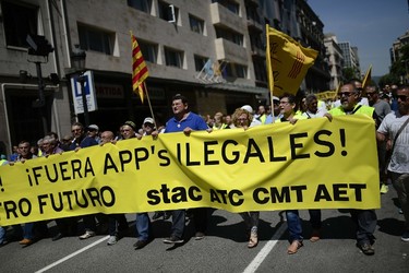 Taxi drivers hold a banner during a strike action in protest of unlicensed taxi-type-services in Barcelona on June 11, 2014. Taxi drivers in London, Paris, Madrid and other European capitals plan to bring chaos to the streets today in protest against unlicensed mobile car-hailing services such as Uber which have shaken up the industry. Banner reads, "Out with illegal apps." (AFP PHOTO/JOSEP LAGO)