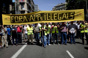 Taxi drivers hold a banner during a strike action in protest of unliccensed taxi-type-services in Barcelona on June 11, 2014. (AFP PHOTO/JOSEP LAGO)