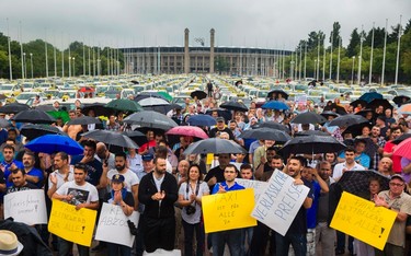 People hold placards during a Europe-wide protest of licensed taxi drivers, denouncing taxi hailing apps that are feared to flush unregulated private drivers into the market, in front of the Olympic stadium in Berlin, June 11, 2014. REUTERS/Thomas Peter