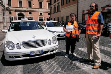 Italian taxi drivers hold a placard reading "Don't take an illegal taxi, take a white regular taxi" during a protest against the growing number of minicabs and cars, known in Italy as "Car rental with driver" (NCC), on June 11, 2014 in Rome. (AFP PHOTO/ANDREAS SOLARO)