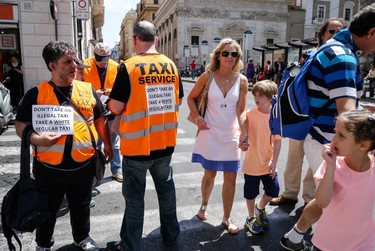 Italian taxis drivers distribute leaflets reading "Don't take an illegal taxi, take a white regular taxi" during a protest against the growing number of minicabs and cars, known in Italy as "Car rental with driver" (NCC), on June 11, 2014 in Rome. (AFP PHOTO/ANDREAS SOLARO)