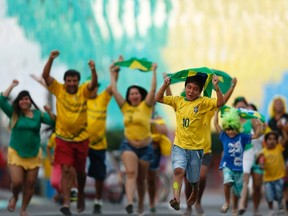 Residents run to celebrate after decorating a street in the colours of Brazil's national flag ahead of the World Cup in the Taguatinga neighbourhood of Brasilia, June 8, 2014. (UESLEI MARCELINO/Reuters)