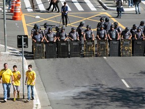 Soccer fans pass riot police blocking protesters during a demonstration against the 2014 World Cup in Sao Paulo, June 12, 2014. (REUTERS/Chico Ferreira)