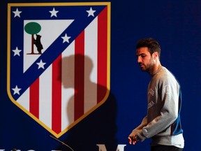 Cesc Fabregas walks in front of an Atletico Madrid coat of arms before a news conference at the Vicente Calderon stadium in Madrid, April 8, 2014. (REUTERS/Paul Hanna)
