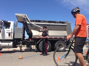 Winnipeg Patrol Sgt. Kevin Cisaroski, centre, and CAN-Bike instructor Dave Elmore demonstrate the perils of blind spots for drivers and cyclists alike at a press conference June 12, 2014 in Winnipeg. (David Larkins/Winnipeg Sun)