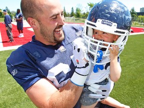 Argos player rep Jeff Keeping — having some fun with his infant son, Bowen, following practice — has shown exemplary leadership qualities in keeping his teammates informed leading up to Thursday’s online ratification vote. (Craig Robertson, Toronto Sun)