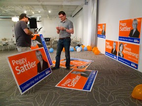 Rob Spencer and Joshua Randall start putting up election posters of their London area MPP's Peggy Sattler and Teresa Armstrong at the NDP election night headquarters at the GoodWill building on Horton in London, Ont. on Thursday June 12, 2014. 
Mike Hensen/The London Free Press/QMI Agency