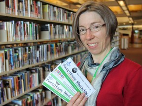 Kimberly Sutherland Mills, manager of programming and outreach for the Kingston Frontenac Public Library, holds the a few of the museum passes at the Isabel Turner branch. Library users can check out one of the 10 passes to get free admission to the three local participating museums. Julia McKay/The Whig-Standard