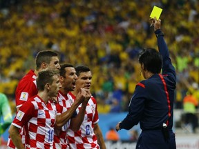 Referee Yuichi Nishimura of Japan shows the yellow card to Croatia's Dejan Lovren, for a foul on Brazil's Fred (unseen), during the 2014 World Cup opening match at the Corinthians arena in Sao Paulo June 12, 2014. (REUTERS/Ivan Alvarado)