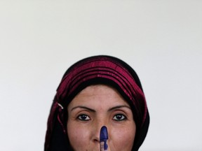 An Afghan woman holds up her ink-stained finger after voting at a polling station in Kabul June 14, 2014. Afghans headed back to the polls on Saturday for a second round of voting to elect a successor to President Hamid Karzai in a decisive test of Afghanistan's ambitions to transfer power democratically for the first time in its tumultuous history. REUTERS/Mohammad Ismail
