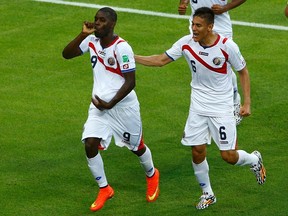 Costa Rica's Joel Campbell (left) carries the ball in his shirt as he celebrates next to teammate Oscar Duarte after scoring against Uruguay during their World Cup match at the Castelao Arena in Fortaleza, Brazil on Saturday, June 14, 2014. (Mike Blake/Reuters)