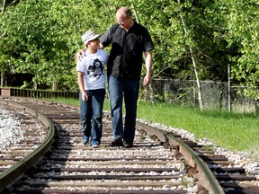 Darren Davis and his son Nicholas Davis, 11, walk along the train tracks in Fort Edmonton Park, in Edmonton on Friday. (DAVID BLOOM/Edmonton Sun)