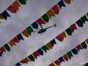 A police helicopter is seen behind decorations for the 2014 World Cup flying over Pelourinho neigborhood in Salvador, June 12, 2014.    REUTERS/Marcos Brindicc