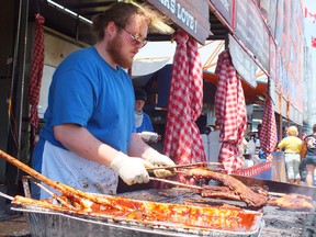 Matt Doerr work the grill for the Kentucky Smokehouse booth at the Sarnia Ribfest. Doerr and his team made the trip from Bear Creek Kentucky. (BRENT BOLES, Sarnia Observer)